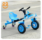 Blue kids tricycle with airplane design, pedals, and glowing rear wheels on pavement