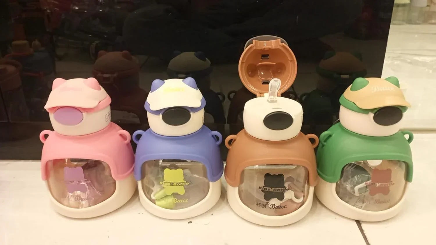 Four colorful kids water bottles with animal ear caps and transparent windows, pink, blue, brown, and green