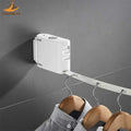 Wall-mounted retractable clothes hanger with multiple wooden hangers holding shirts on grey tiled wall