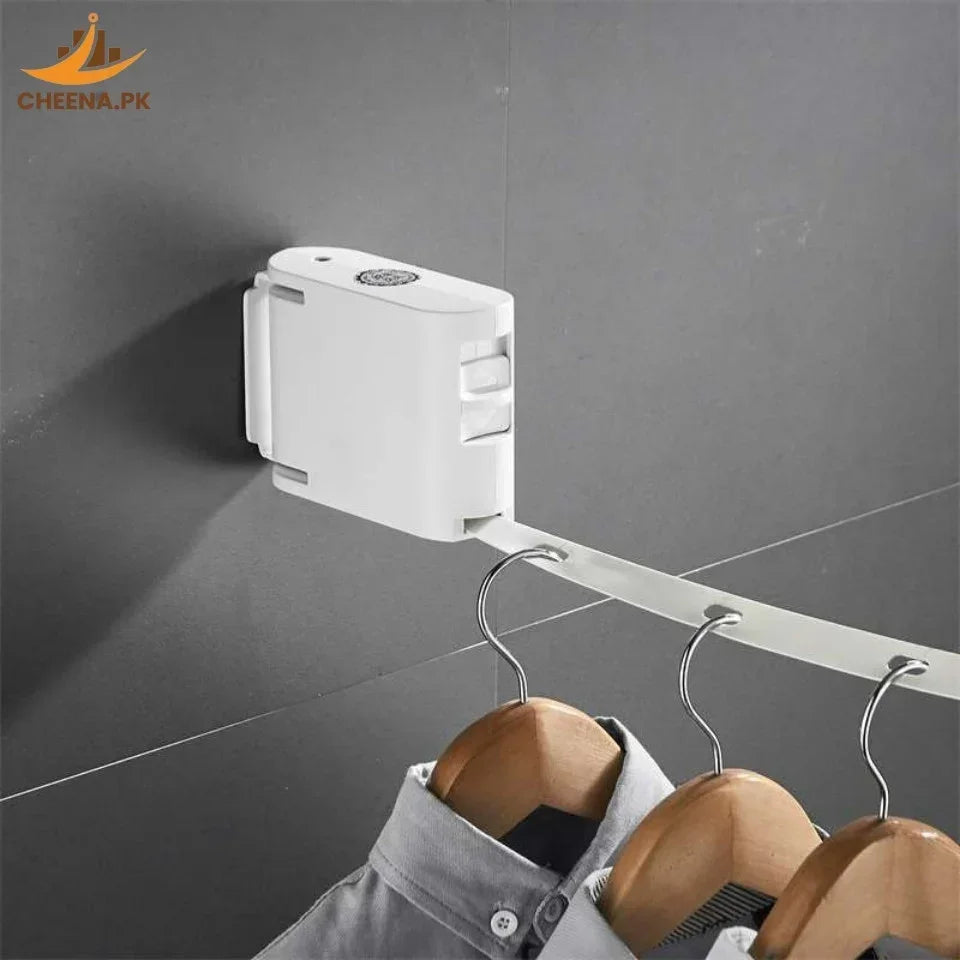 Wall-mounted retractable clothes hanger with multiple wooden hangers holding shirts on grey tiled wall