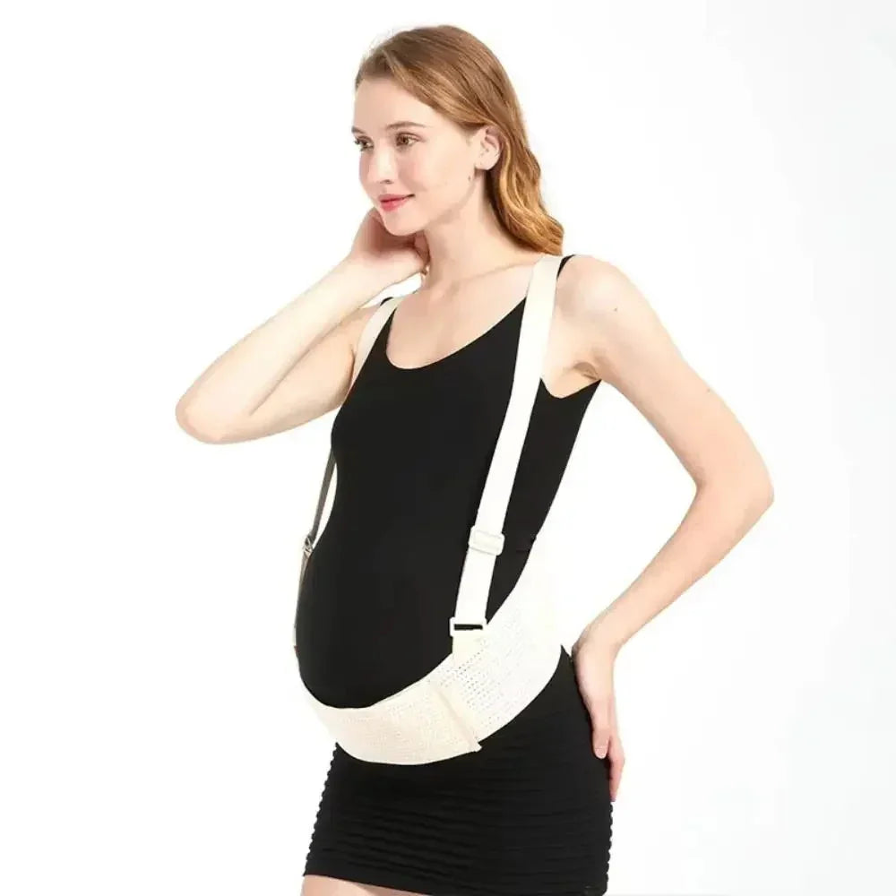 Pregnant woman wearing a white maternity support belt over a black dress on a white background