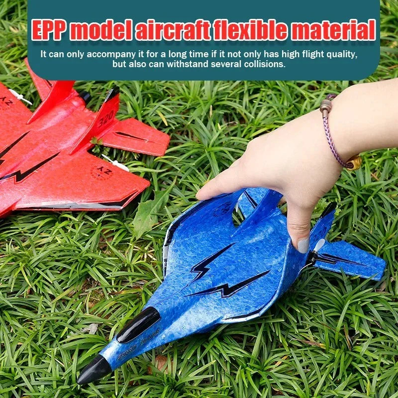 Hand holding blue flexible EPP model aircraft toy on grass next to red model plane