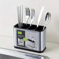 Stainless steel cutlery holder with compartments containing chopsticks, forks, knife, and spoon on kitchen counter