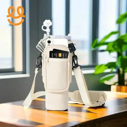 beige crossbody water bottle carrier with front zipper pocket holding phone, credit card, keys, and cash on wooden table