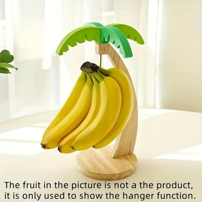 wooden banana hanger with green palm leaf design holding ripe bananas on white table