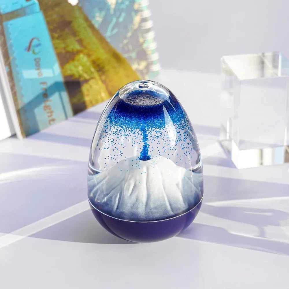 Blue and white sand timer with swirling sand inside on a white surface with book and glass block background