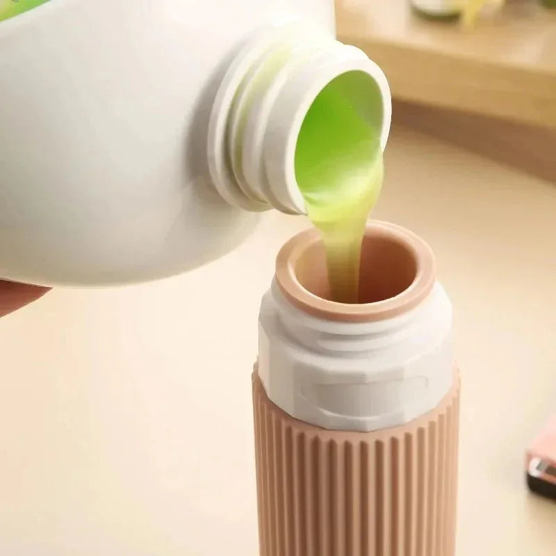 Pouring green liquid from white bottle into beige portable travel diffuser bottle