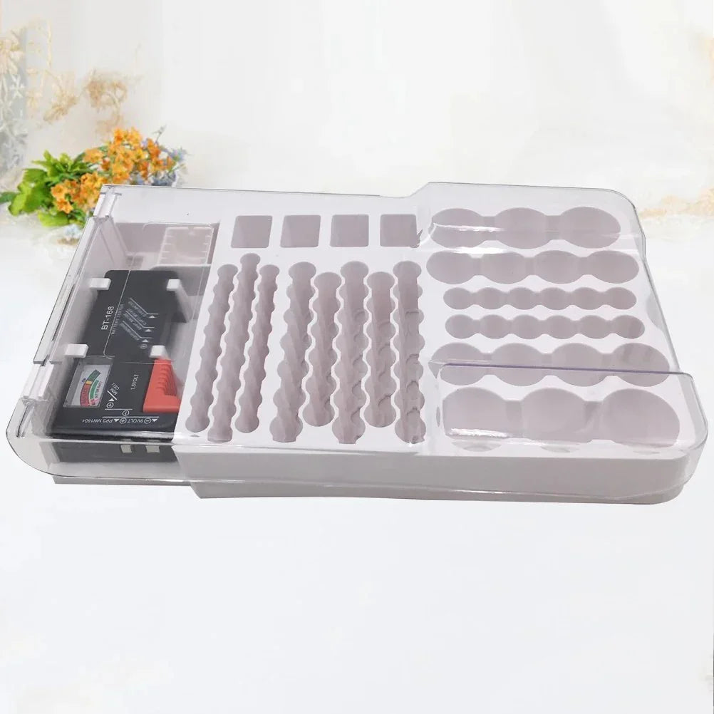 Clear plastic organizer tray with multiple shaped compartments and a small black electronic device inside