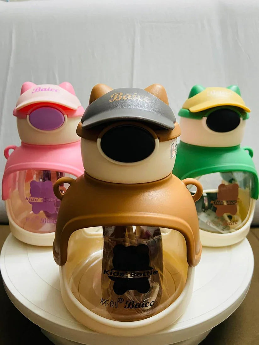 Three colorful Baice kids bottles shaped like bears wearing caps in brown, green, and pink on white surface