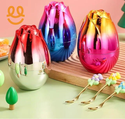 Colorful metallic rose-shaped candy containers on wooden board with floral small forks on green table