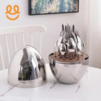 Modern stainless steel cutlery set with forks, spoons, and knives in a sleek round holder on a marble table