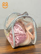 Transparent toiletry bag with pink slippers, pink velvet fabric, and bath sponge on wooden surface