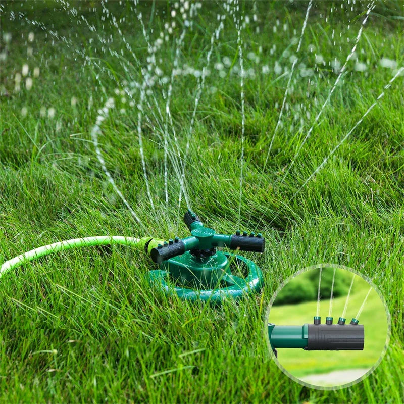 Green rotating lawn sprinkler spraying water over lush green grass with hose attached