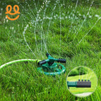 Green rotating lawn sprinkler spraying water over lush green grass with hose attached