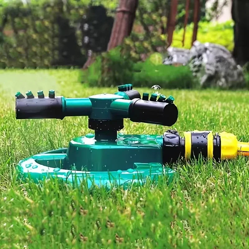 Rotating green and black garden sprinkler watering lush green grass with garden background