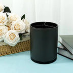 Black cylindrical pen holder on blue desk with white roses in basket and stacked books