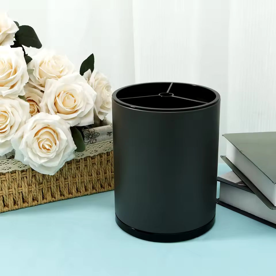 Black cylindrical pen holder on blue desk with white roses in basket and stacked books