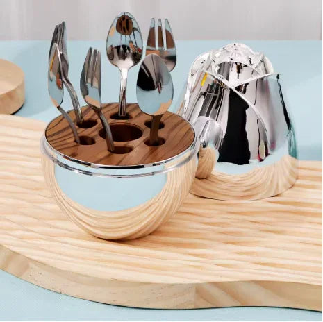 Modern silver cutlery holder with spoons and forks on wooden and pastel blue surface