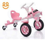 Pink and white toddler tricycle with large front wheel, rear swivel caster wheels, and a playful airplane design