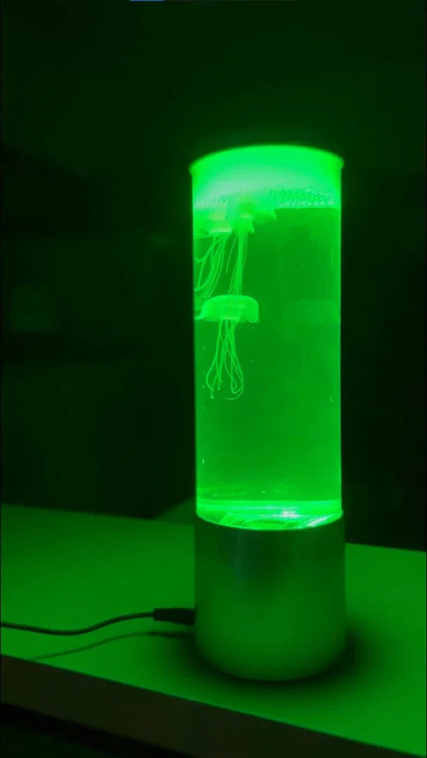 green illuminated jellyfish lamp on a table in dark room with visible jellyfish inside