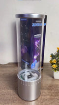 Luminess jellyfish lamp with transparent cylindrical body and silver base on wooden surface next to yellow flower pot