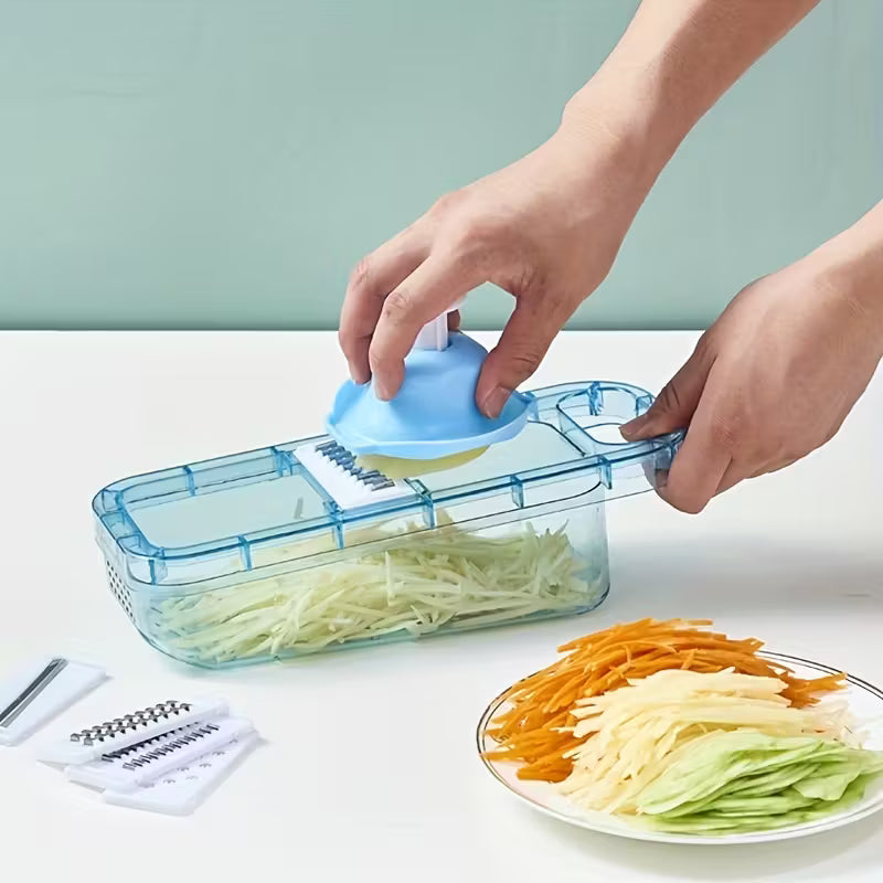 Hands using blue vegetable slicer with container to shred potatoes near plate with shredded carrots and cucumbers