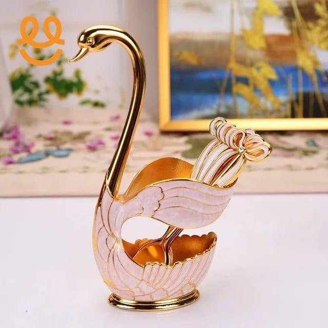 Elegant pink and gold swan-shaped decorative tray with matching gold utensils on white surface