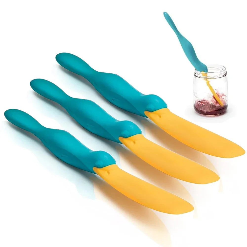 Set of three duck-shaped spreader knives with teal handles and yellow blades, one in jar of jam