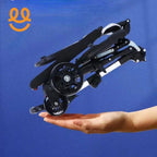 Compact folded black stroller with wheels held on open palm against blue background