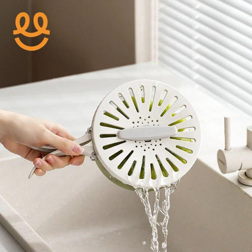 Hand holding white vegetable strainer draining water over kitchen sink with faucet and window blinds