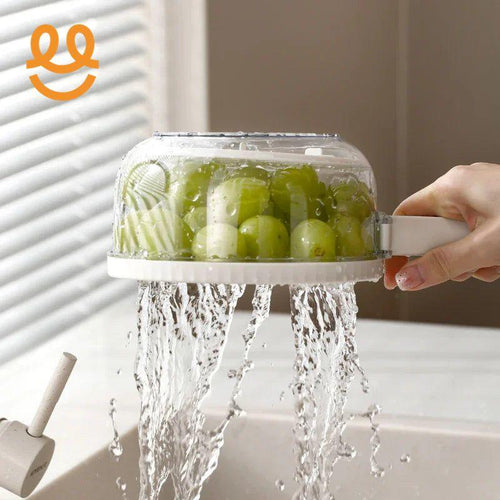 Hand holding white fruit washer draining water from green grapes over kitchen sink