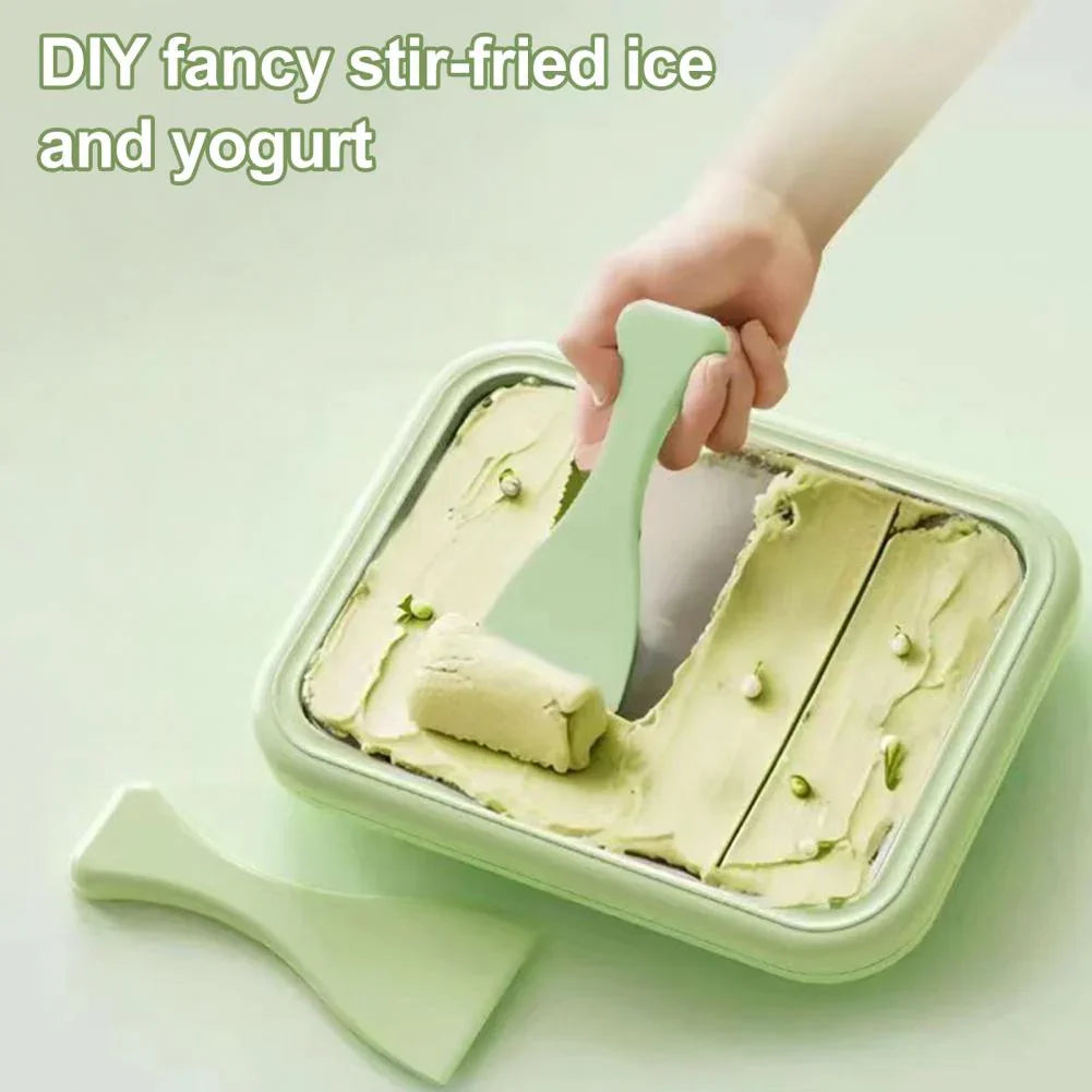 Hand using a green spatula to stir-fry light green frozen yogurt in a rectangular container on a light surface