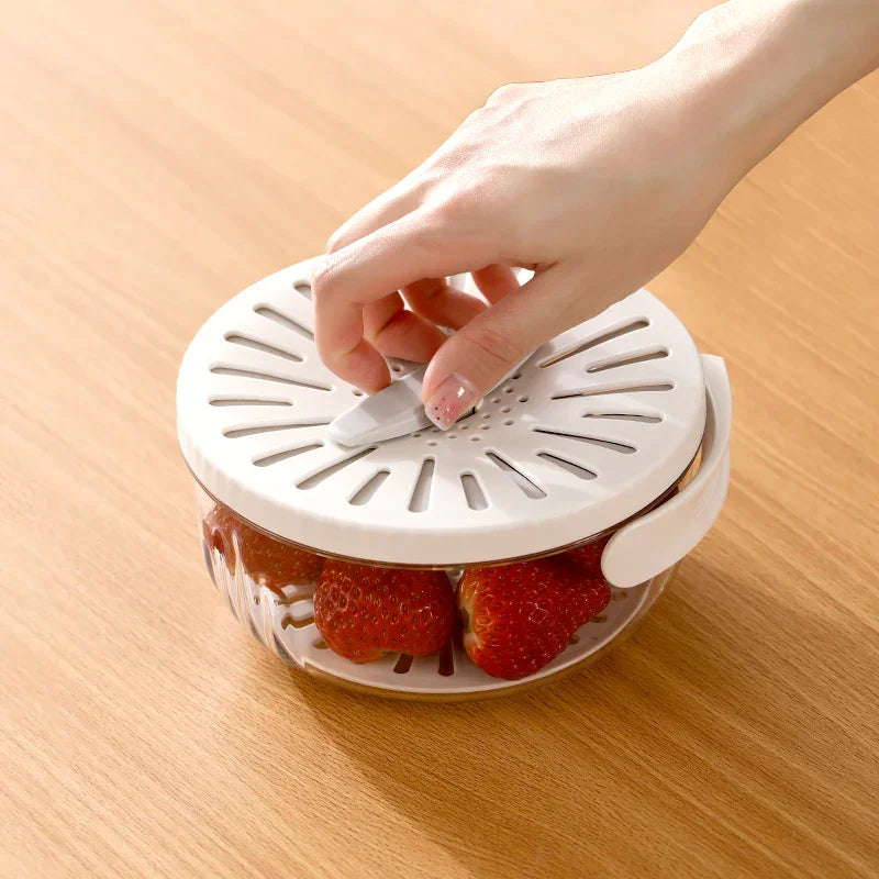 Hand adjusting white vented lid on clear plastic container holding fresh strawberries on wooden table