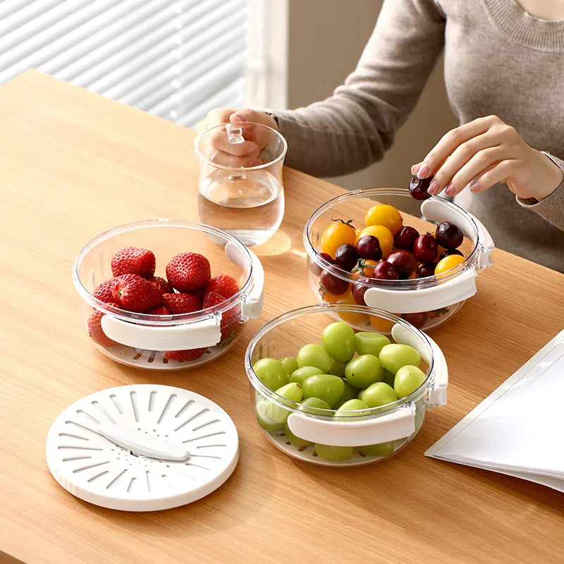 Woman holding cherry tomatoes near clear bowls of strawberries, grapes, and water on wooden table